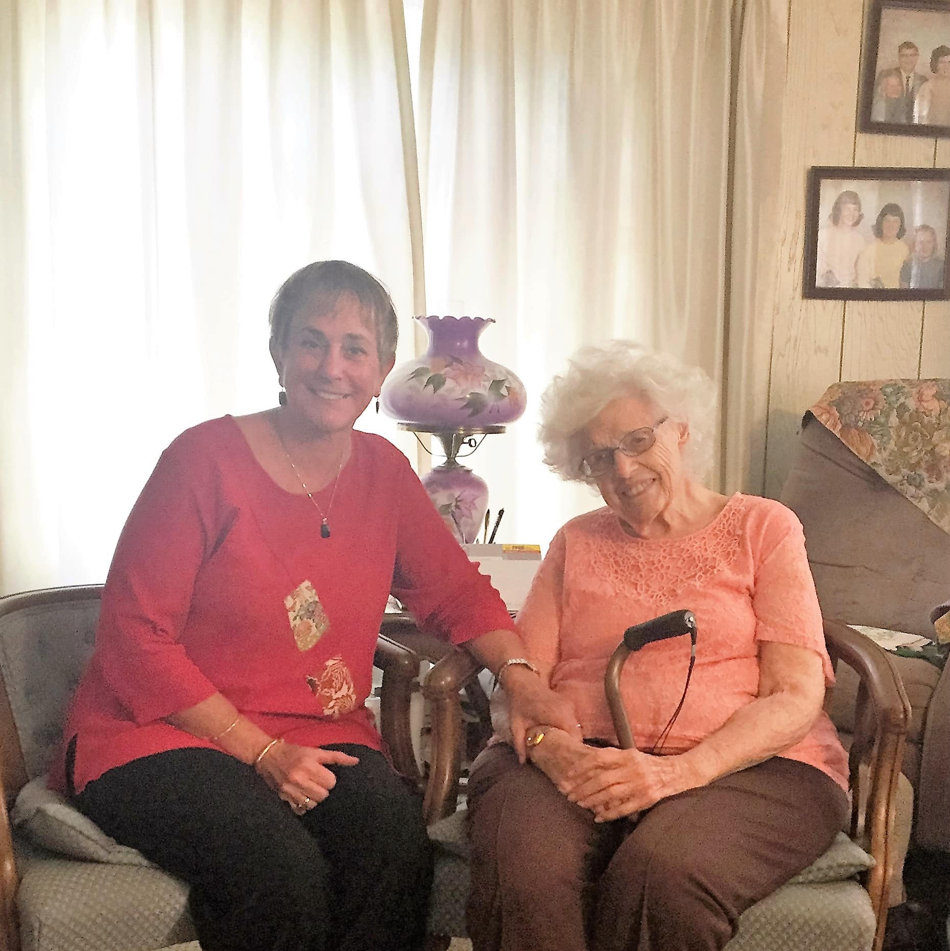 Two women sit on armchairs smiling