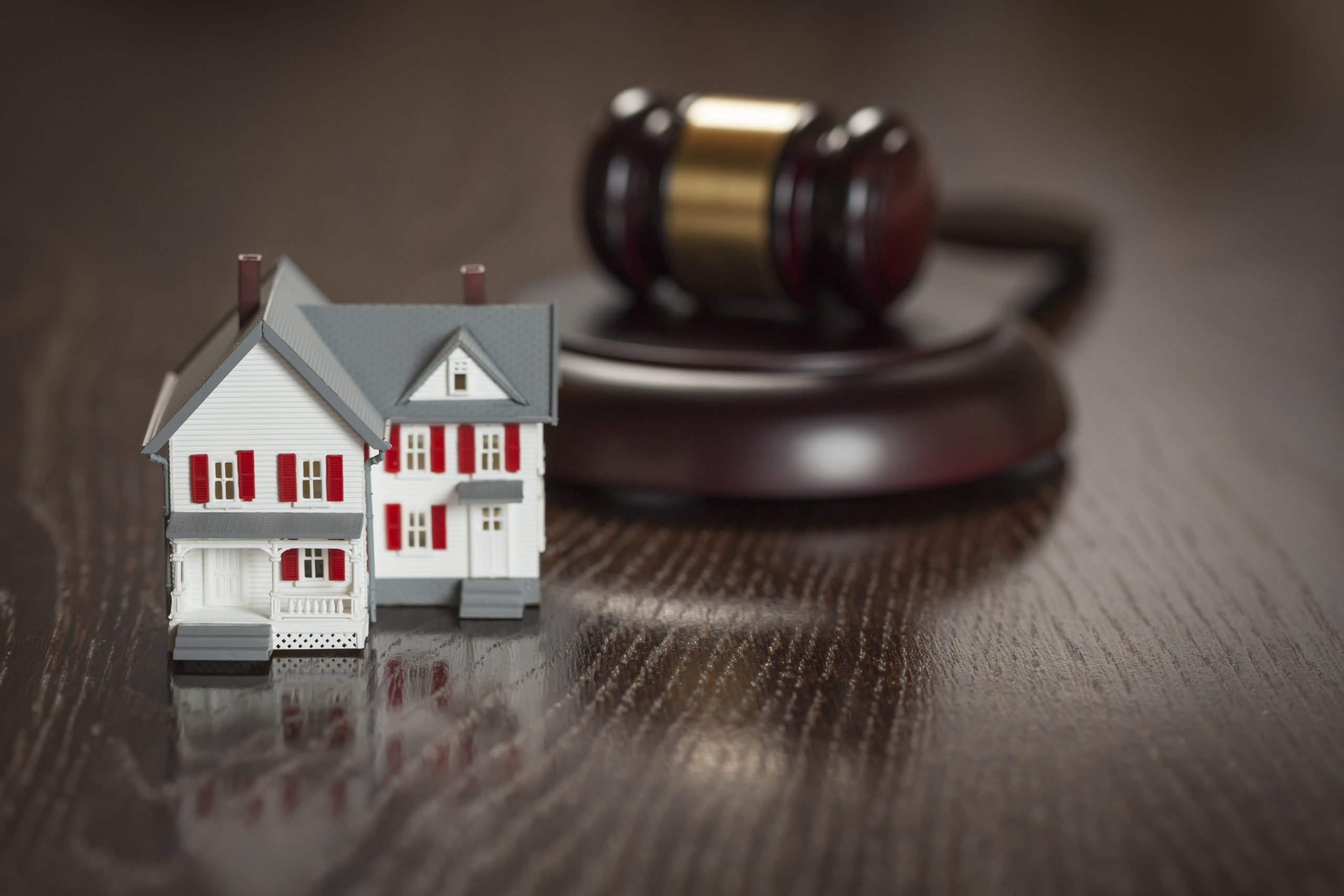 Gavel And Small Model House On Wooden Table